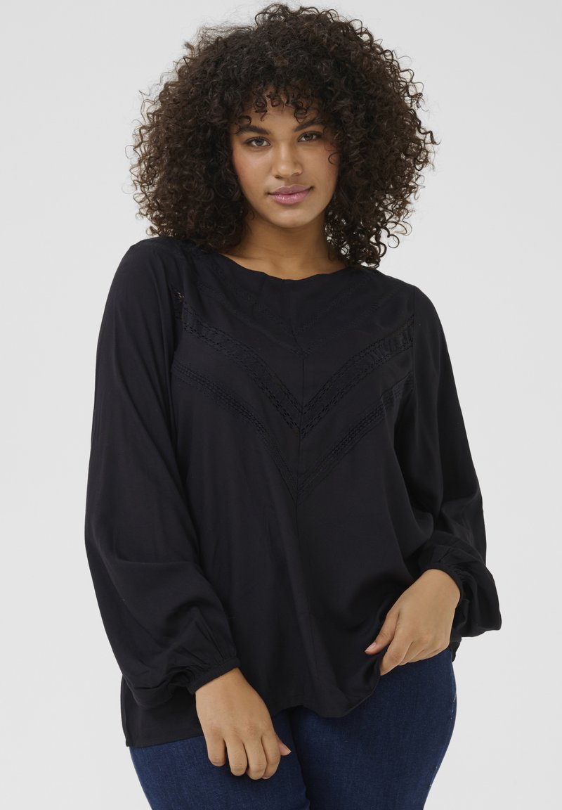 Black, long-sleeve blouse featuring a woven lace detail in a chevron pattern on the front. Soft fabric with gathered accent at cuffs.