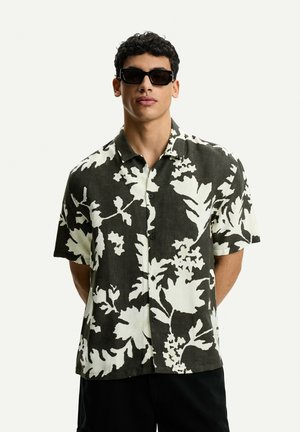 Short-sleeved shirt in dark green and white floral pattern, made of lightweight fabric with a button-up collar and relaxed fit.