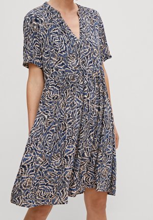 Woman wearing short-sleeve, knee-length dress with blue, black, and beige abstract pattern, front buttons, and V-neck collar.