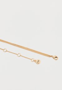 Colier din aur cu două șiruri, unul cu inele circulare și o etichetă circulară gravată cu "DKNY", având un închizător de tip homar.