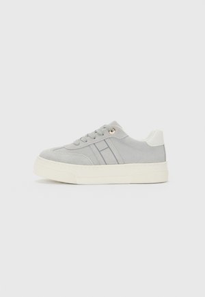 Hellgraue Wildleder-Sneaker mit weißer Sohle, grauen Seitenstreifen, weißem Fersenpatch und grauen Schnürsenkeln auf weißem Hintergrund.