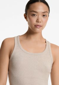 Beige geripptes Tanktop mit rundem Ausschnitt und breiten Schulterträgern, ausgestattet mit einer glatten Textur und taillierter Passform.