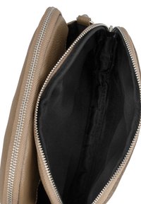 Tanskleurige leren clutch met metalen rits, met een zwarte binnenvoering. Het ontwerp is eenvoudig zonder opvallende patronen of hardware.