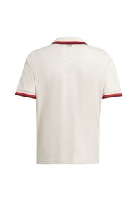 Polo shirt crème avec un motif texturé, accents rouges sur les manches et le col. Le dos comporte un logo dans une couleur dorée subtile.