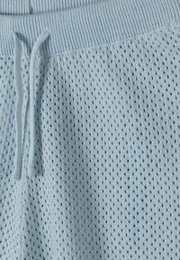 Shorts tricotés bleu clair avec ceinture côtelée et cordon de serrage, présentant un motif texturé et ventilé sur tout le tissu.