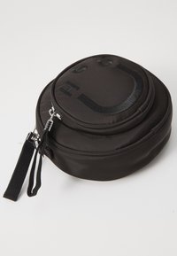 Borsa rotonda in tessuto nero con chiusura a zip, caratterizzata da un design di un sorriso sollevato. Include un manico testurizzato e una finitura morbida.