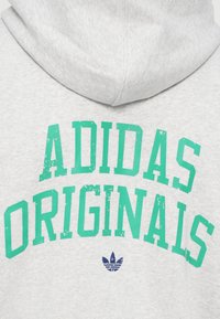 Szara bluza z kapturem z tealowym, zniszczonym tekstem "ADIDAS ORIGINALS" oraz małym granatowym logo na dole. Miękka faktura materiału.