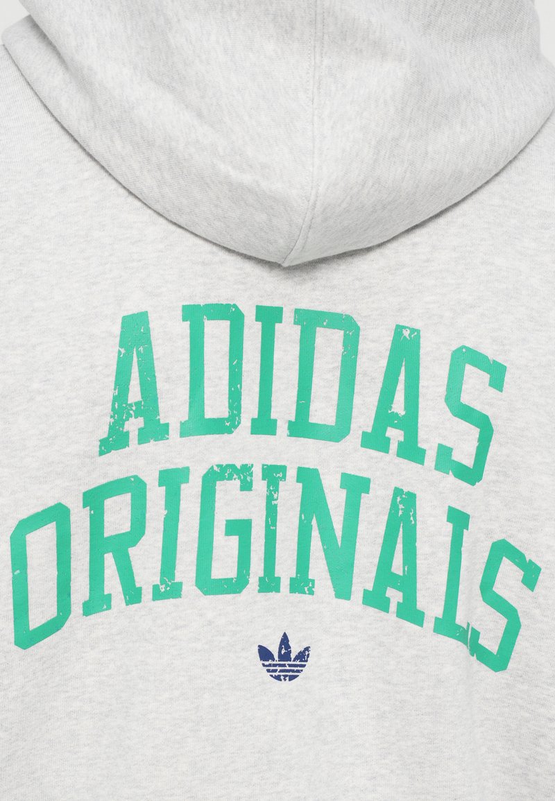 Grå hættebluse med teal distressed tekst "ADIDAS ORIGINALS" og et lille marineblåt logo nederst. Blødt stof.