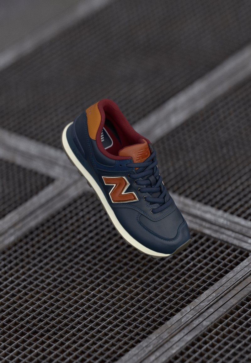 Blue leather sneaker with brown accents, gray sole, and textured surface. Features a prominent "N" logo on the side and lace-up design.