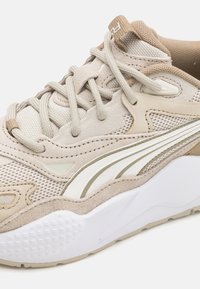 Világos bézs sneaker, hálós és velúr anyagokkal. Fehér középtalppal, texturált talppal és diszkrét barna részletekkel rendelkezik. Lekerekített orr kialakítás.
