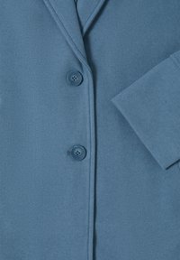 Blazer de mezcla de lana azul con solapa muesca, dos botones frontales y detalle de manga doblada. Textura suave con costuras sutiles.