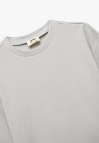 Jasnoszary sweter z teksturowanym wzorem waflowym, okrągłym dekoltem i ściągaczami na rękawach. Zawiera metkę z marką "Korean Kids".