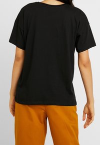Black, short-sleeve T-shirt made of cotton with a relaxed fit. The back features a simple design and a crew neckline.