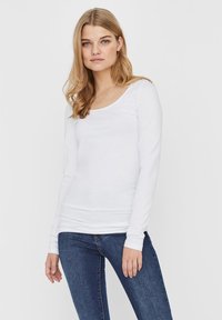 Wit langlijf t-shirt van zacht katoen, met een ruime halslijn en een aansluitend ontwerp, gecombineerd met blauwe denim jeans.