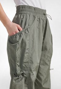 Letvægts, åndbare cargobukser i en afdæmpet grøn farve med elastisk taljebånd, flere lommer og mesh-detaljer.