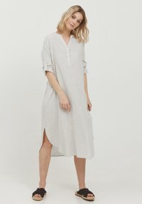 Hellgraues Leinenkleid in knielanger Schnittform mit einer Knopfleiste vorne, Kragen und hochgestellten Ärmeln. Verfügt über seitliche Schlitze für optimalen Bewegungsfreiheit.