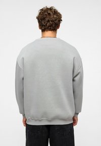 Grijze sweatshirt met een ronde hals, geribbelde manchetten en onderrand. Soepele textuur en ontspannen pasvorm; geen zichtbare patronen of ontwerpelementen.