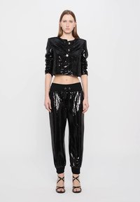 Zwarte pailletten cropped jas met ronde halslijn en knoopsluiting, gecombineerd met bijpassende pailletten joggers met elastische tailleband en boorden.