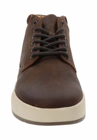 Scarpa casual in pelle marrone con lacci neri e suola in gomma bianca vista frontalmente su uno sfondo bianco.