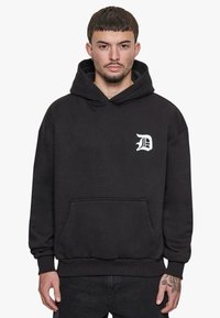 Schwarzer Kapuzenpullover aus einem Baumwollmischgewebe. Mit einer Vordertasche und einem gestickten weißen Logo auf der Brust. Rippbündchen an den Ärmeln und am Saum.