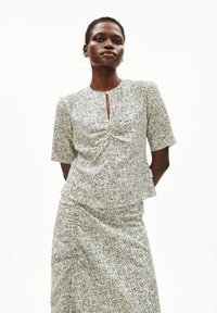 Blumenmuster-Oberteil und Rock-Set in hellem Beige mit marinefarbenen Akzenten. Kurze Ärmel, Rundhalsausschnitt und geraffte Details an der Taille. Glatte Textur.