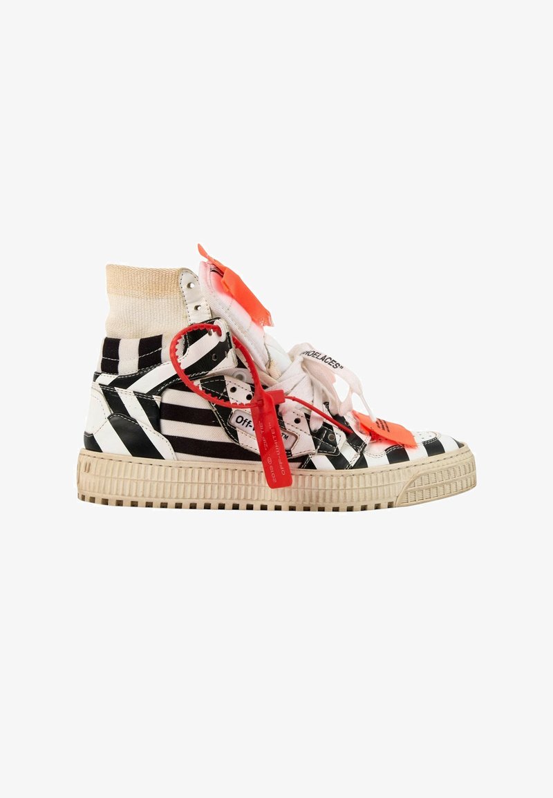 Baskets montantes avec des rayures diagonales noires et blanches, des lacets blancs marqués d'une étiquette en plastique rouge, et une semelle beige usée.