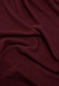Tessuto bordeaux con un aspetto morbido, sottile e Texture, con un motivo a coste e pieghe drappeggiate. Adatto per capi di abbigliamento o accessori.