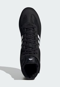 Černá sportovní bota s síťovaným svrškem, strukturovaným povrchem a bílými akcentními pruhy. Má zaoblenou špičku a ploché šňůrky.