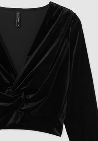 Blusa in velluto nero con scollatura profonda a V e maniche lunghe, caratterizzata da un dettaglio annodato nella parte anteriore. Texture liscia, design corto.