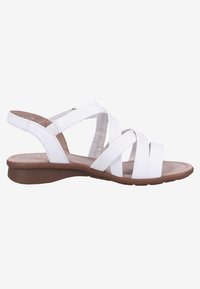 Sandale blanche en cuir avec brides croisées, bout ouvert, semelle basse marron et bride arrière avec fermeture Velcro.