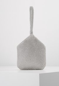 Sac à main en maille argentée avec un motif diamant unique. Il présente une poignée singulière et une forme géométrique, mettant en valeur une surface texturée.