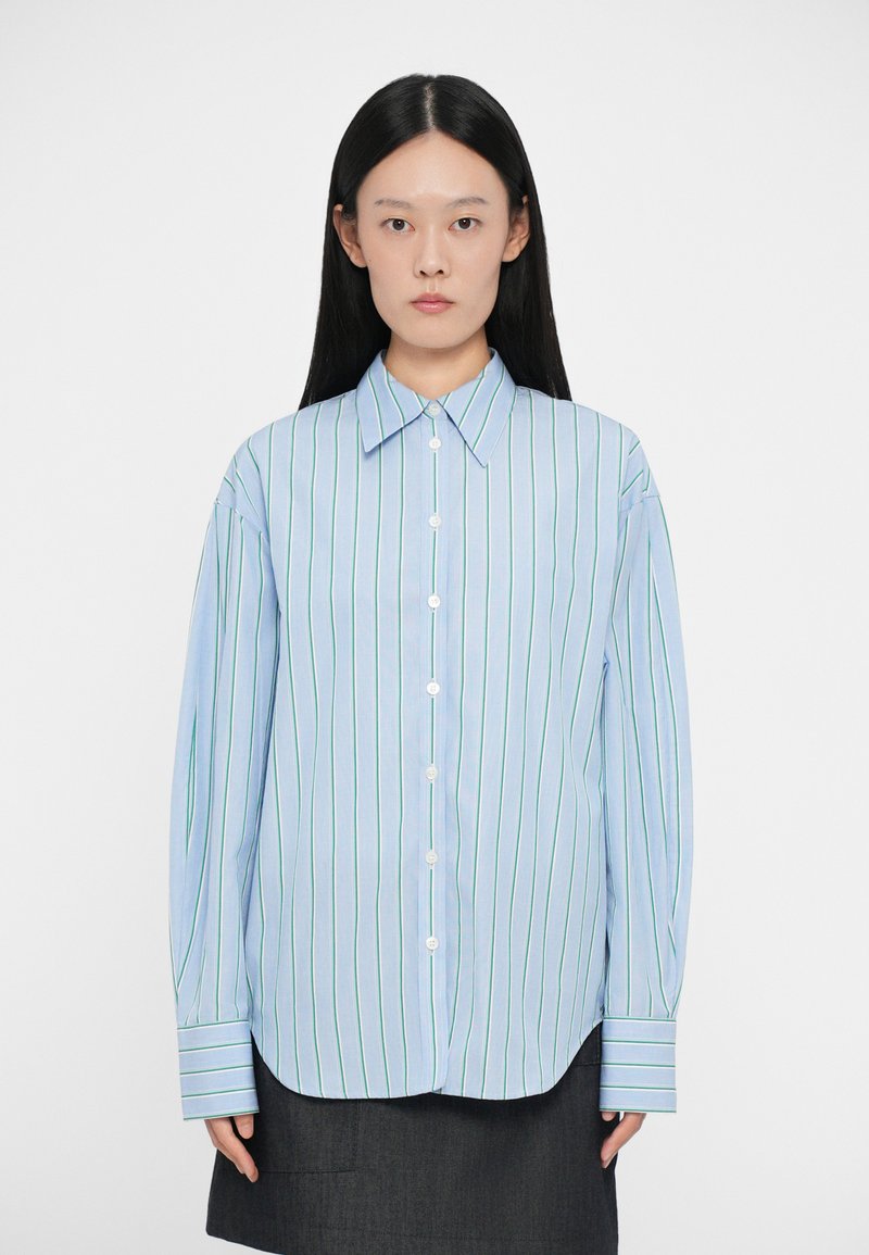Camicia button-up azzurro chiaro con righe verticali verdi e bianche. Presenta un colletto alla francese e maniche lunghe e morbide con dettagli ai polsini.