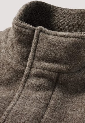 Nahaufnahme eines braunen Wollmantelkragens mit einer weichen, flauschigen Textur und detaillierten Nähten.