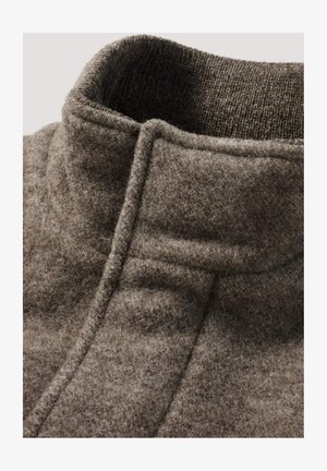 Nahaufnahme eines braunen Wollmantelkragens mit einer weichen, flauschigen Textur und detaillierten Nähten.