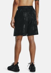 Zwarte sportieve shorts met een glanzende afwerking, elastische tailleband en een losse pasvorm. Met zijnaad en een gladde textuur.