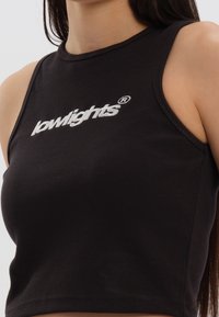 Top corto in cotone nero a coste con scollo rotondo, dotato di logo "lowlights" ricamato in bianco sul davanti. Progettato per una vestibilità aderente.