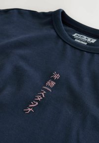 Navyblaues, locker sitzendes T-Shirt mit vertikalem, rosa besticktem japanischem Text auf der Vorderseite und rundem Ausschnitt.
