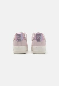 Sneakers Nike Air in suede rosa chiaro con suole in gomma bianca. Caratterizzati da accenti metallici del logo e un design a taglio basso.