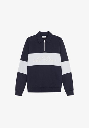 Tumši zils džemperis ar baltu horizontālu svītru un rāvējslāpi. Uz svītras izšūts "Les Deux" krēmkrāsā. Mīksta auduma, klasiskas formas.