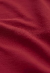 Burgundy kangas, joka on sileä tekstuuriltaan ja sisältää hienovaraisia poimuja sekä pienen kiillon, laskostettuna, jotta syvyys ja taitteet näkyvät.