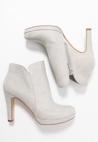Graue Wildleder-Ankle Boots mit runder Zehenform, hohem Absatz und seitlichem Reißverschluss. Das Design verfügt über eine gewellte Oberkante und eine glatte Textur.