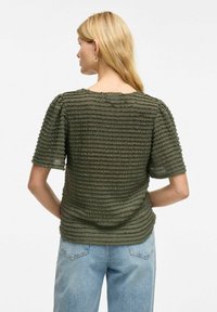 Top texturizado en verde oliva que presenta rayas horizontales, mangas cortas y un cuello redondo. La tela en capas añade profundidad al diseño.
