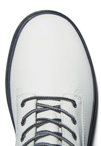 Vita lädersko med mörka snören, med en texturerad ovandel, rund tå och kontrasterande svart kant längs sulan för detalj.