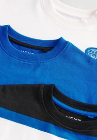 Tre t-shirts staplade: en vit, en ljusblå med rund hals och en svart med blå ränder. Mjukt bomullstyg; ribbade kragar.