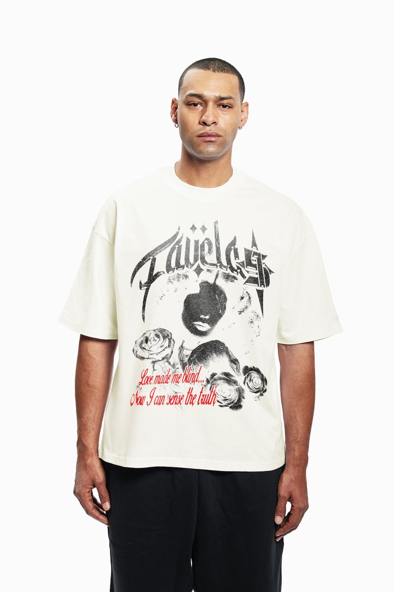 Cream oversized t-shirt with graphic print featuring a face, roses, and text in red and black. Short sleeves, round neckline, cotton material.