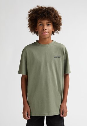 T-shirt verde in cotone con maniche corte, scollo rotondo, con un piccolo logo nero sul lato sinistro del petto. Vestibilità casual e tessuto liscio.