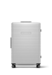 Silver hard-shell suitcase with vertical grooves, top handle, and four black wheels for mobility. Features a smooth texture and compact design.