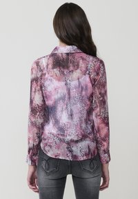 Camisa de manga larga transparente en tonos de rosa y púrpura, con un patrón mixto texturizado. El cuello es clásico y el corte es relajado.