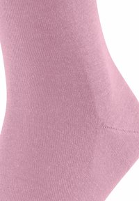 Calzino rosa chiaro realizzato in morbido tessuto a coste, con una superficie liscia e una forma aderente, dotato di una zona della punta rinforzata.