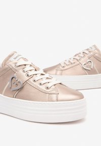 Metallic light pink platform sneakers, featuring white laces, silver heart accent, smooth texture, and a rounded toe design.